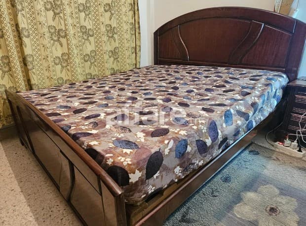 un lit double avec matelas et deux tables de nuit presque ne